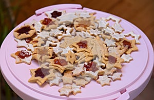 Pile of baked stars and superhero, handmade cookies on a pink stand