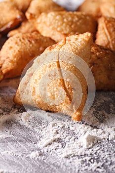 Pile of baking samosas on a floured table. Vertical