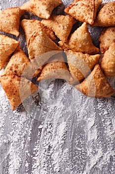 A pile of baking samosas on a floured table. vertical top view