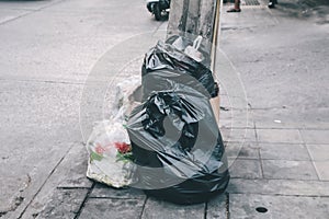 Pile of black garbage on the footpath at side road in big city, pollution trash Black plastic bag