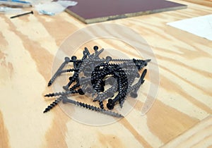 A pile of black self tapping screws isolated.