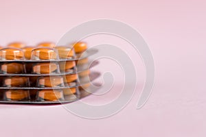 Pile of blisters with medicine pills on pink background. Stack of tablets, capsules