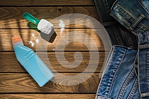 Pile of blue jeans clothes with detergent and washing powder on