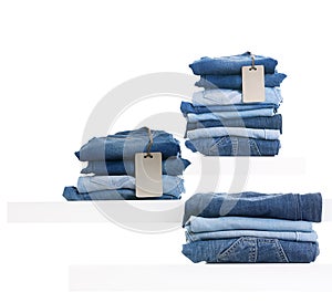 Pile of blue jeans with tag label on white shelf