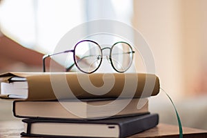 Pile of book and eyeglasses on bedside table