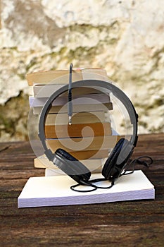 A pile of books audio headset on a wooden table