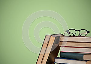 Pile of books and glasses against green background