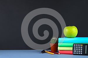 A pile of books and stationery on a chalkboard background. Work desk, education, school.