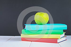 A pile of books and stationery on a chalkboard background. Work desk, education, school.