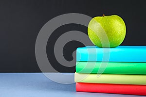 A pile of books and stationery on a chalkboard background. Work desk, education, school.