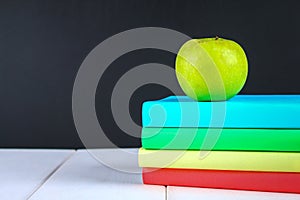 A pile of books and stationery on a chalkboard background. Work desk, education, school.