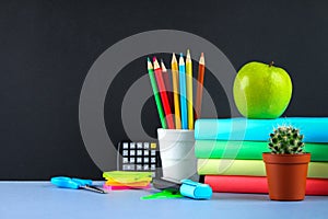 A pile of books and stationery on a chalkboard background. Work desk, education, school.