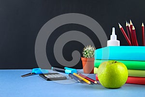 A pile of books and stationery on a chalkboard background. Work desk, education, school.