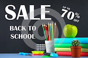 A pile of books and stationery on a chalkboard background. Work desk, education, school. SALE.