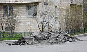 Pile of broken asphalt lies near the wall of an apartment building