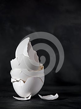 A pile of broken white egg shells on a dark background