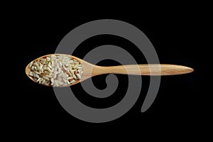 Pile of brown rice with spoon isolated on Black Background