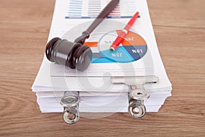 A pile of business documents with a hammer and a signature pen