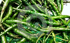 Pile of cabai hijau keriting or Capsicum annum or green chili on display at market photo