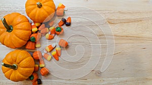 Pile of candy corn and mini pumpkins on a wooden background