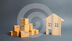 A pile of cardboard boxes and a residential house. Concept of moving to another house or city. beginning of a new stage of life