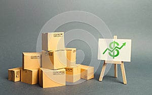 A pile of cardboard boxes and a stand with green arrow up. Increasing consumer demand. rate growth of production of goods