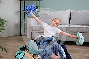 Pile of carelessly scattered clothes on floor.The child puts things in order in the room