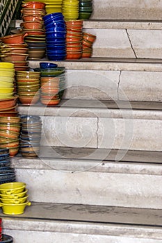 Pile of ceramic bowls of various sizes and colors on stairs