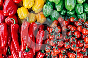 Pile of cherry tomatoes and bell peppers nicely arranged at Farmer`s market