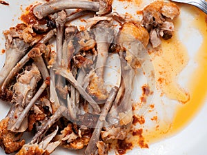 Pile of chicken wings bones on a white plate. Popular poultry product. Finished meal