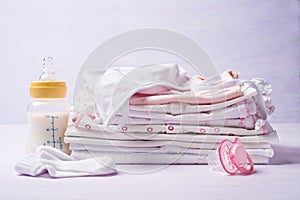 Pile of childrens clothing with a bottle of milk and pacifier
