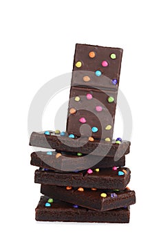 pile of chocolate fudge brownies with candy pieces on white