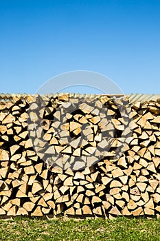 Pile of chopped firewood, green grass and blue sky