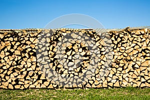 Pile of chopped firewood, green grass and blue sky