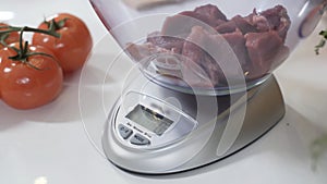 Pile of chopped meat on electronic scale in kitchen. Standing on flat weighing platform. Electronic scale with liquid