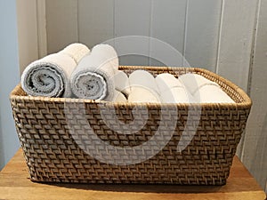 Pile of cloth, hand towel, table napkin, handkerchief on the basket in spa, bath room, toliet with blur white wooden wall backgrou