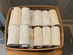 Pile of cloth, hand towel, table napkin, handkerchief on the basket in spa, bath room, toliet with blur white wooden wall backgrou