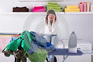 Pile Of Clothes And Iron On Ironing Board