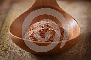 Pile of cocoa powder in wooden spoon