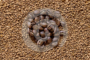 Pile of cofee seeds on instant granulated cofe background