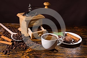 Pile of coffee beans besides open grinder