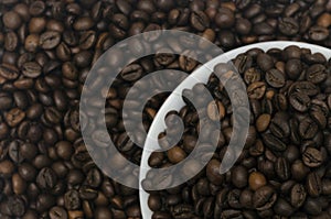 A pile of coffee beans in a white saucer with beans in the background