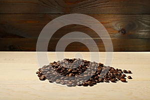 Pile of coffee beans is on a wooden background