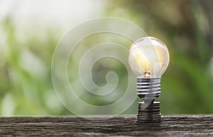 A pile of coins placed on a stick with a light bulb on top of the coin