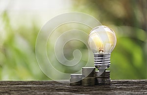 A pile of coins placed on a stick with a light bulb on top of the coin