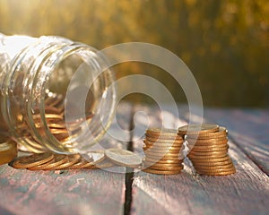 Pile of coins on the wooden table with natural light. Saving conceptual.