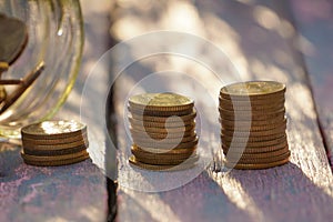 Pile of coins on the wooden table with natural light. Saving conceptual.