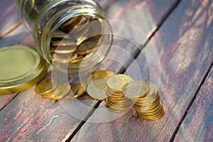 Pile of coins on the wooden table with natural light. Saving conceptual.