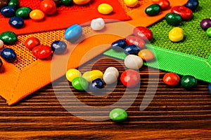 Pile of colorful candy drops isolated on wood background.