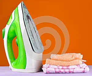 Pile of colorful clothes and irons, on pastel wooden plank